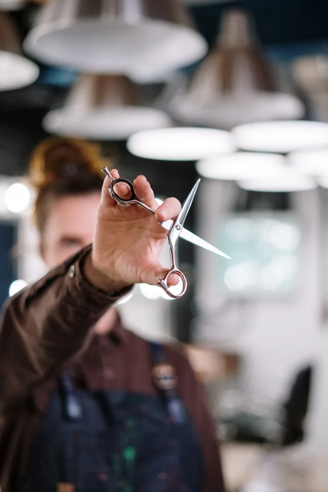 A hairstylist holding scissors; reference photography by cottonbro studio.